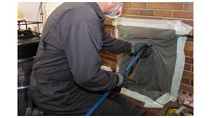 Professional chimney sweep working on chimney with specialized cleaning equipment